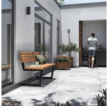 Uteplats med trä- och metallbänk, planterad blomlåda, utekök och stående person