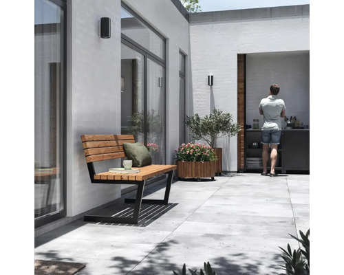 Uteplats med trä- och metallbänk, planterad blomlåda, utekök och stående person