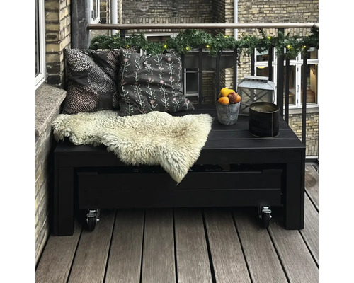 Balkongmöbler med kuddar och dekoration på en balkong med trägolv och tegelvägg