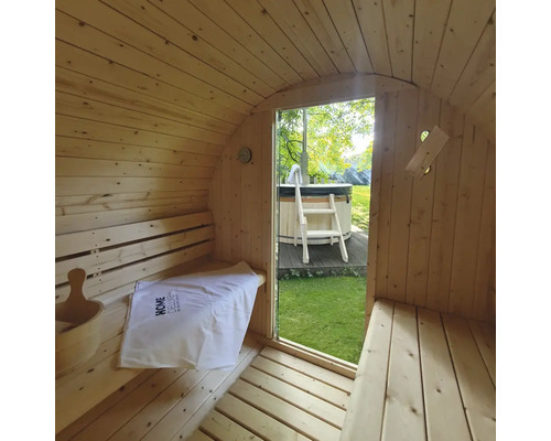 Interiör av en bastutunna i trä med utsikt över en bubbelpool i trädgården.