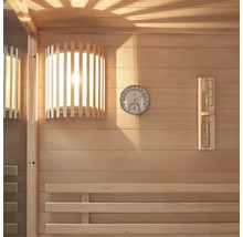Interiör av en bastu med träpanel, lampa, termometer och hygrometer.