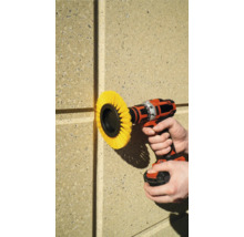 En borrmaskin med borstfäste används på en husvägg.