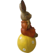Påskharefigur som sitter på ett gult ägg som dekoration