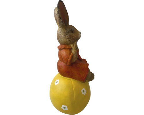 Påskharefigur som sitter på ett gult ägg som dekoration