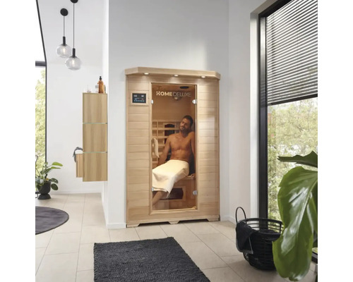Interiörbild av ett badrum med en Home Deluxe bastu och en man med en handduk