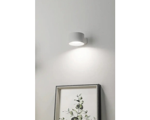 Vägglampa bredvid en inramad bild på väggen