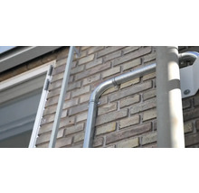 Installerad takränna av metall på en tegelvägg