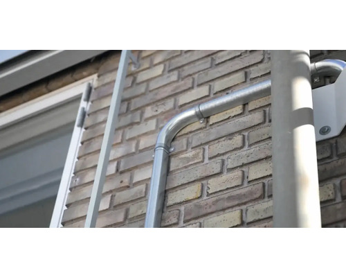 Installerad takränna av metall på en tegelvägg