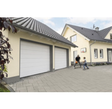 Dubbla garageportar på ett bostadshus, medan en far spelar basket med sin son.