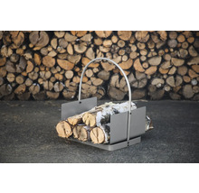 Vedkorg av metall med vedträn framför en stapel ved