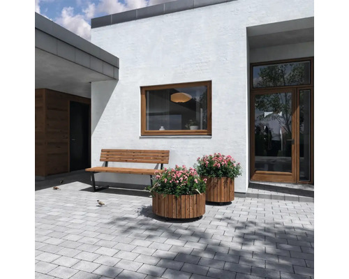 Utomhusområde med bänk, blomlådor och gatsten framför ett hus