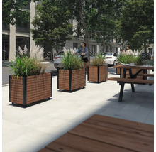 Utomhusscen med blomlådor i trä och metall samt en picknickbänk i trä och metall.