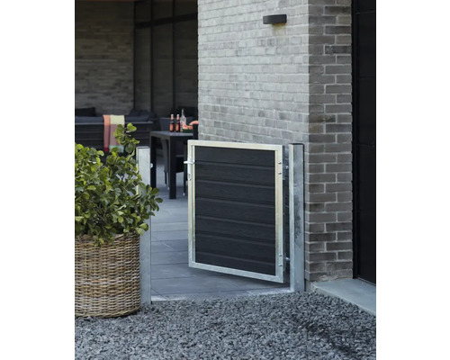 Trädgårdsscen med en liten grind av metall och trä, en blomlåda och en terrass