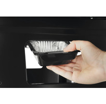 En hand sätter in en fettuppsamlingsbricka i en grill.