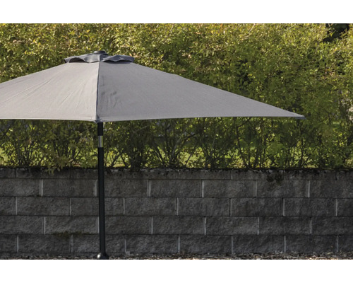 Grått trädgårds parasoll med mast framför en stenmur