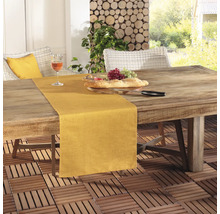 Scen med ett matbord utomhus med bordslöpare, bröd, druvor och ett glas vin.