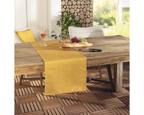 Scen med ett matbord utomhus med bordslöpare, bröd, druvor och ett glas vin.