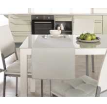 Matbord med bordslöpare, porslin och stolar i ett kök.