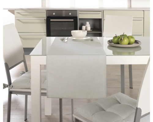 Matbord med bordslöpare, porslin och stolar i ett kök.