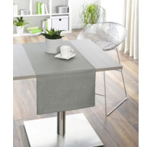 Matbord med bordslöpare, växt och porslin i ett ljust rum