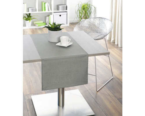 Matbord med bordslöpare, växt och porslin i ett ljust rum