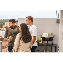 Scen med tre personer på en takterrass med grill.