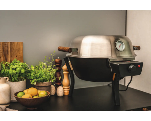 Elektrisk grill med temperaturdisplay och trädetaljer på ett bord med ingredienser