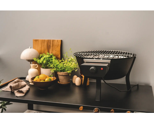 Elektrisk grill på ett bord med växter och citrusskal