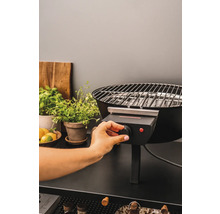 En person använder en elektrisk grill på ett bord