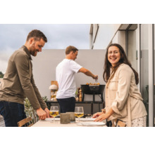 Grupp människor förbereder en måltid på en utomhusgrill.