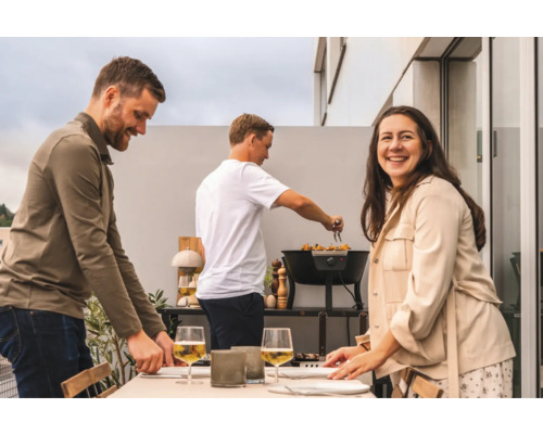 Grupp människor förbereder en måltid på en utomhusgrill.