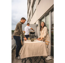 Tre personer förbereder en måltid på en balkong med grill.