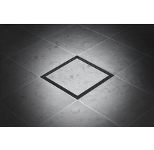 Fyrkantigt golvbrunn av metall på klinkergolv.