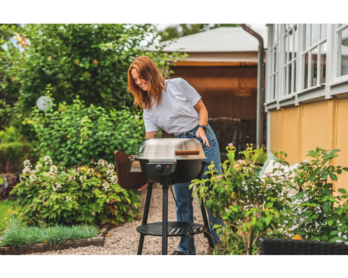 Kvinna förbereder en klotgrill i trädgården.