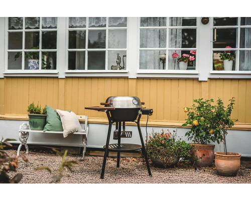 Utomhusscen med grill, bänk och krukväxter framför ett hus