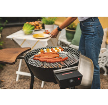 Elektrisk grill med korvar och grönsaksspett på grillgallret, i trädgården.