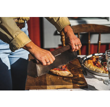 En person skär pizza med en pizzaskärare på en träskiva.