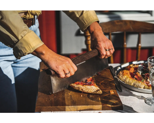 En person skär pizza med en pizzaskärare på en träskiva.