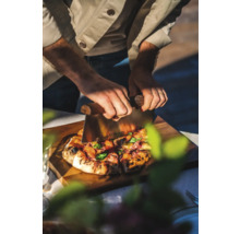 En person skär pizza med en pizzaskärare på en skärbräda i trä.