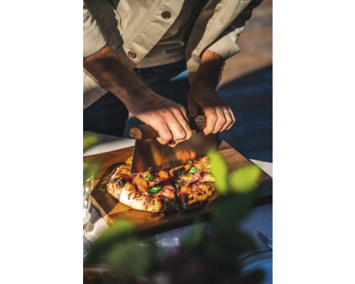 En person skär pizza med en pizzaskärare på en skärbräda i trä.