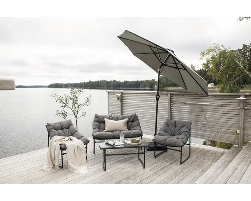 Terrass vid sjön med loungemöbler, parasoll och soffbord