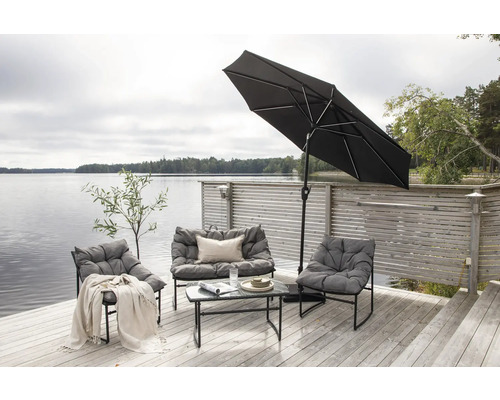 Trädgårdssittgrupp med parasoll på en träterrass vid en sjö