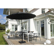 Trädgårdsscen med parasoll, bord, stolar och loungeset på en träaltan framför ett vitt hus