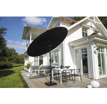 Svart parasoll på en terrass med trädgårdsmöbler framför ett hus