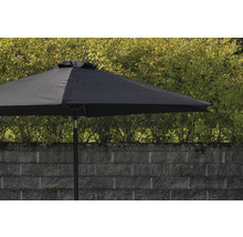 Svart trädgårdsparasoll framför en mur