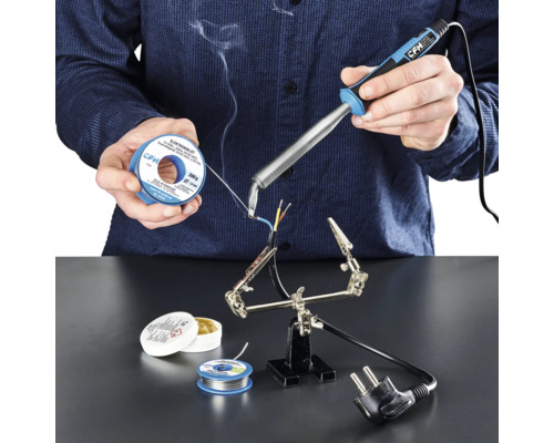 Lödkolv CFH E 100 Person löder kablar med lödkolv, lödtenn och flussmedel på en arbetsyta.