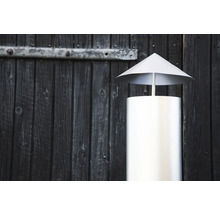 Skorstenshuv av rostfritt stål framför en trävägg