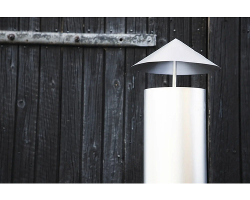 Skorstenshuv av rostfritt stål framför en trävägg