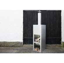 Modern trädgårdskamin i rostfritt stål med vedförvaring.