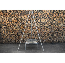 Grillstativ med ved framför trävägg